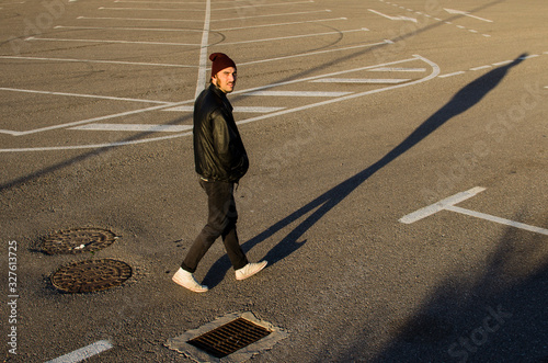 young cool man dressed in leather walking on the asphalt photo