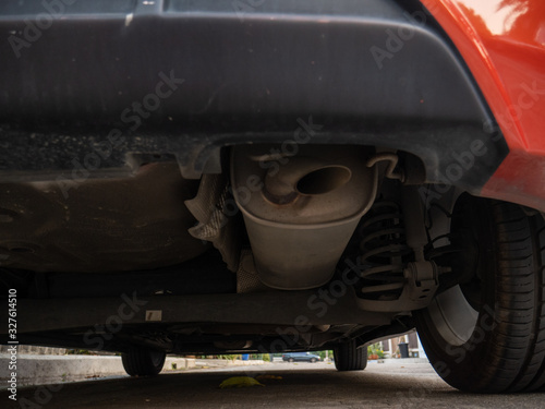 Exhaust system under an orange car on the roadside