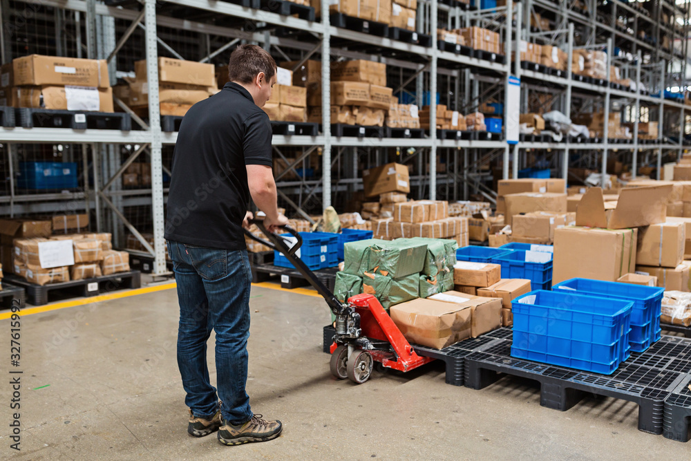 Fototapeta premium Warehouse worker dragging hand pallet truck or manual forklift with the shipment pallet unloading into a truck. Distribution, Logistics Import Export operation, Trading, Shipment, Delivery concept