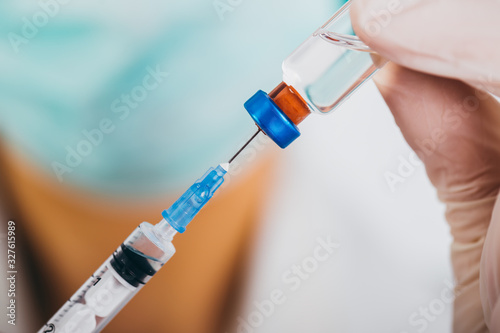 Vaccine bottle and syringe in a doctors hands close-up.  COVID-19/ Coronavirus concept.
