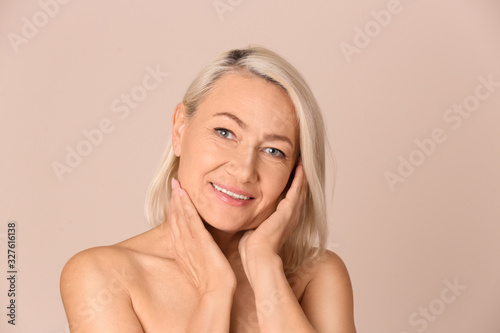 Portrait of beautiful mature woman on beige background