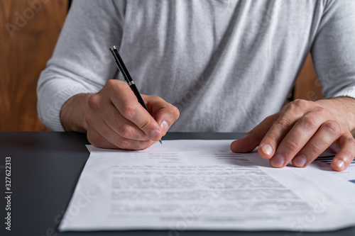 A man signing the mortgage contract at the real property agent office. The concept of entering into legal power to take liabilities. Casual wearing.