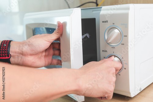 Woman's Hands Closing Microwave Oven Door And Preparing Food in microwave.