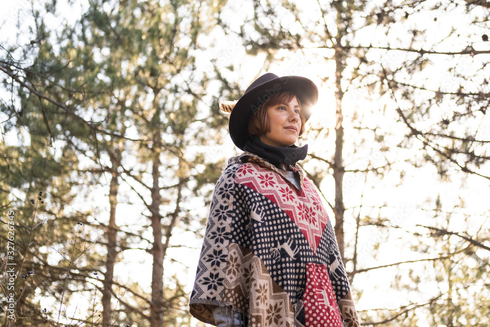 Yong hipster woman traveler in hat and poncho walking outdoors Yong hipster woman traveler in hat and poncho walking outdoors