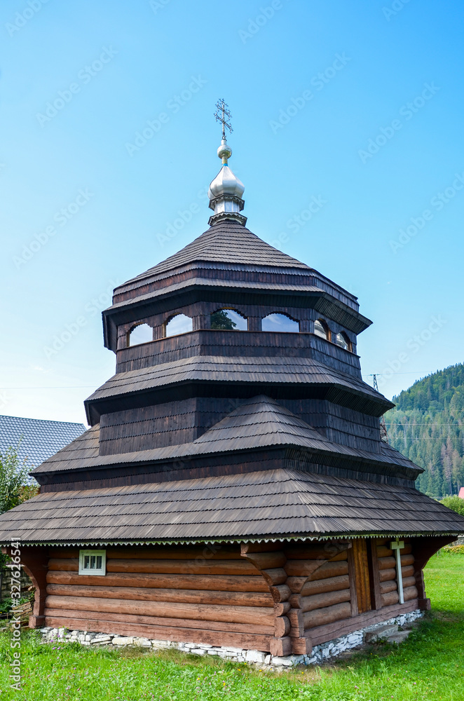  Small rustic brown wooden church on top of hill in countryside. Europe. Ukraine. Vertical color photography.