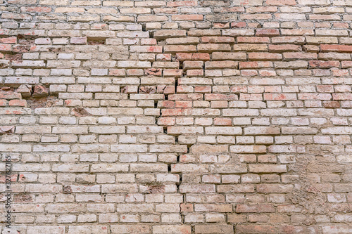 ancient building with cracks in wall made of red bricks located in historical building