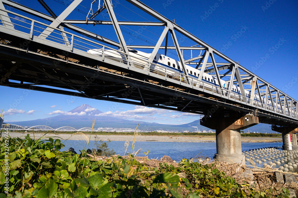 Naklejka premium High Speed Bullet Train Shinkansen ran across Fuji river with Fuji Mountain Background in Winter Clear Sky Day, Fuji City, Shizuoka