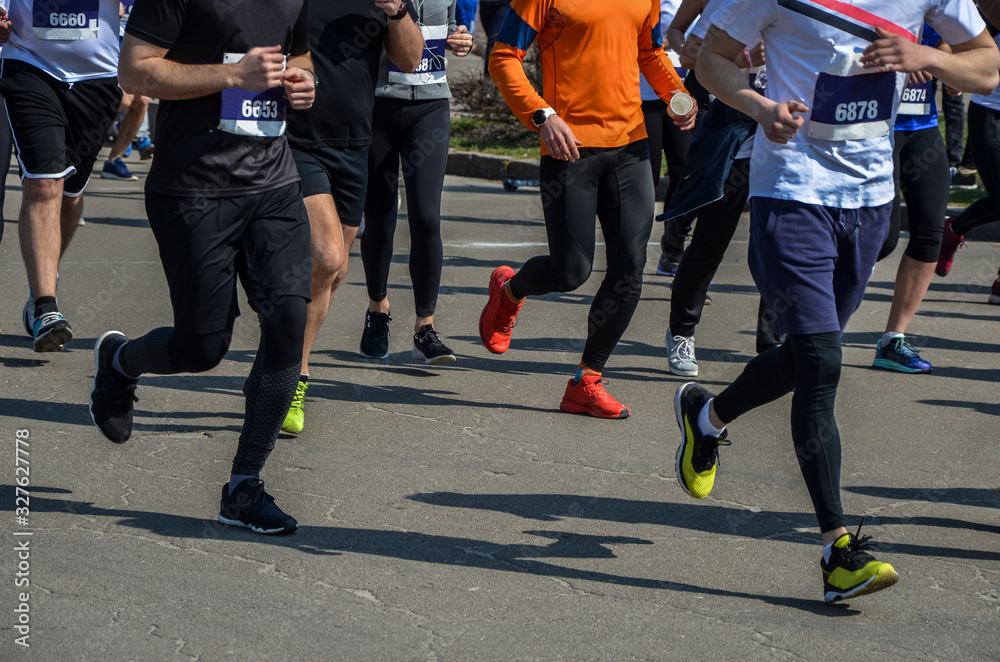 Detail of a group of runners during a city marathon. Legs and sneakers. Muscles under stress. Sport concept