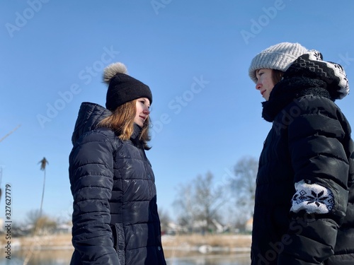 two teenage girls sisters in winter clothes talking outdoors
