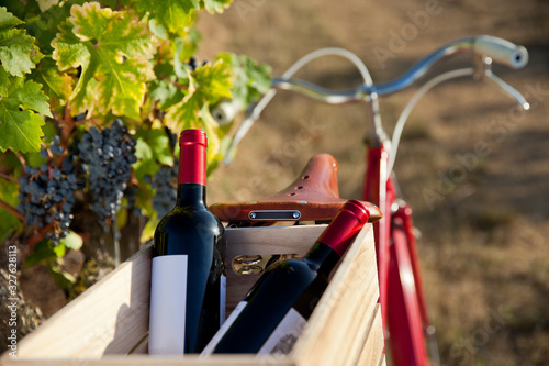 Vélo rouge et caisse de vin rouge dans les vignes.