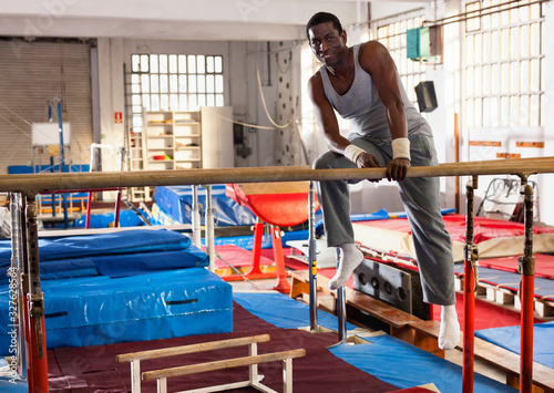 Portrait of man in sportswear doing exercises on parallel bars at gymnastic hall