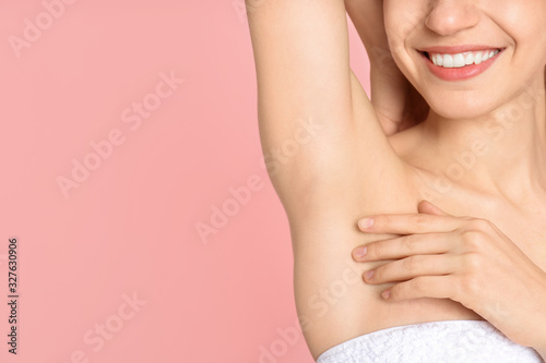 Young woman showing armpit with smooth clean skin on pink background  closeup. Space for text