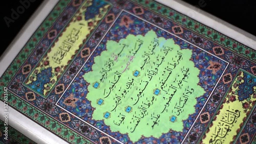 Hands turning the pages of the Quran reading surah Al-Fatiha and surah Al-Baqarah, on black background, Closeup shot.