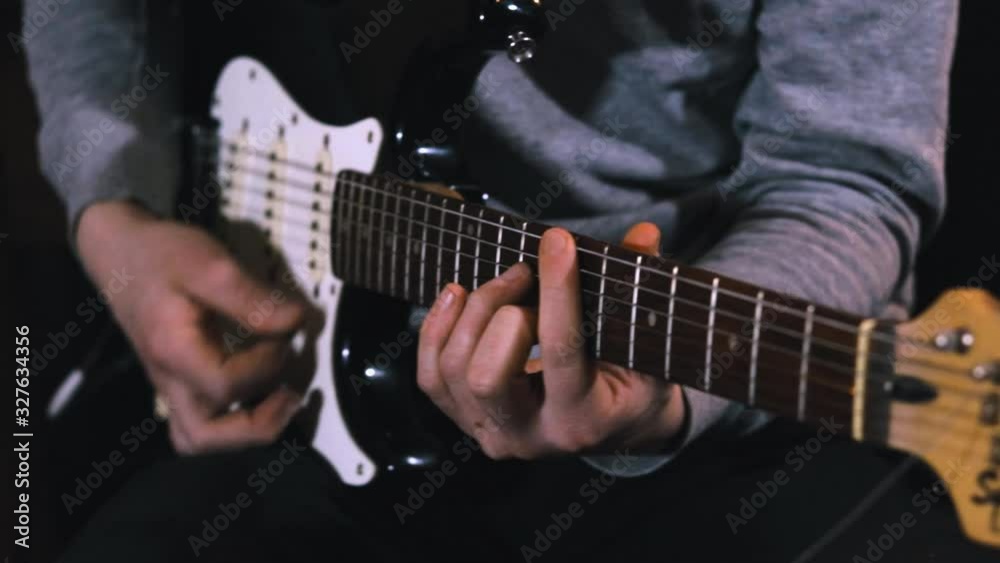 Guitarist hits the strings of the electric guitar, close up mens fingers playing music on guitar Guitarist hits the strings of the electric guitar, close up mens fingers playing music on guitar