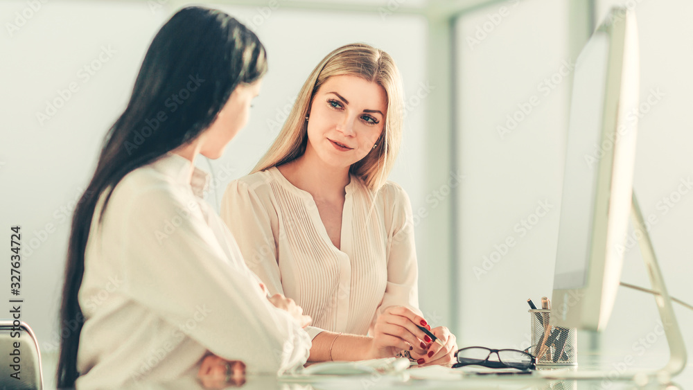 two employees are discussing something sitting at the office ta two employees are discussing something sitting at the office ta