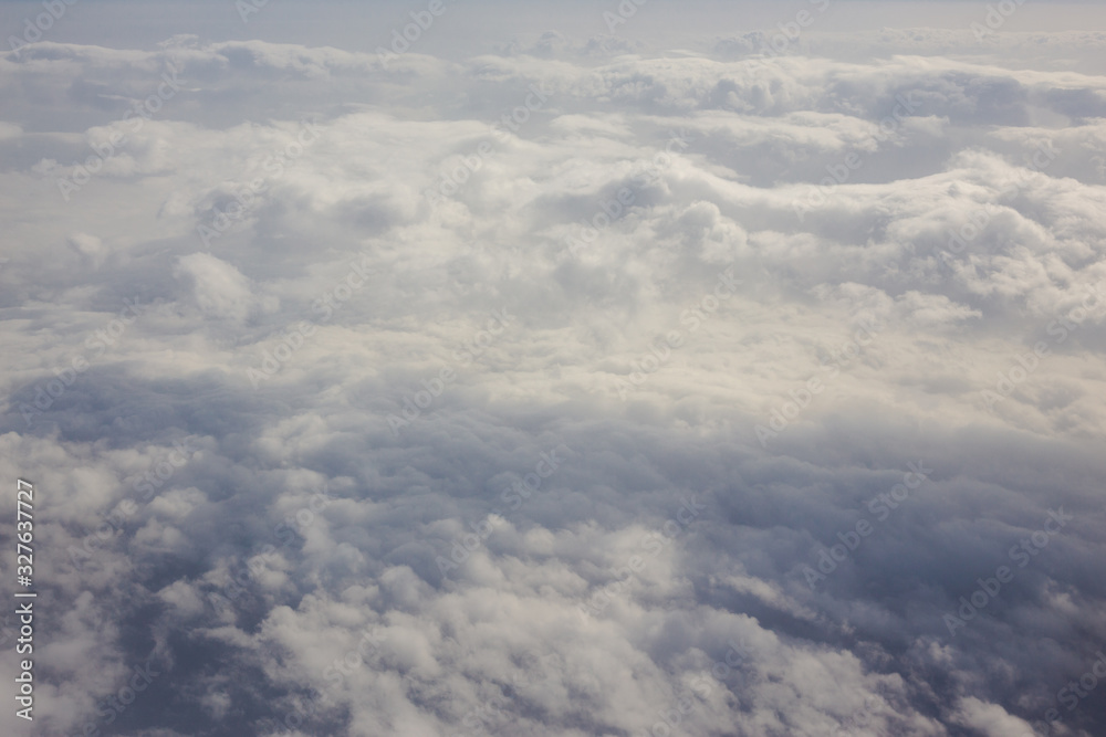 Aerial sky and fluffy clouds background. View from airplane porthole