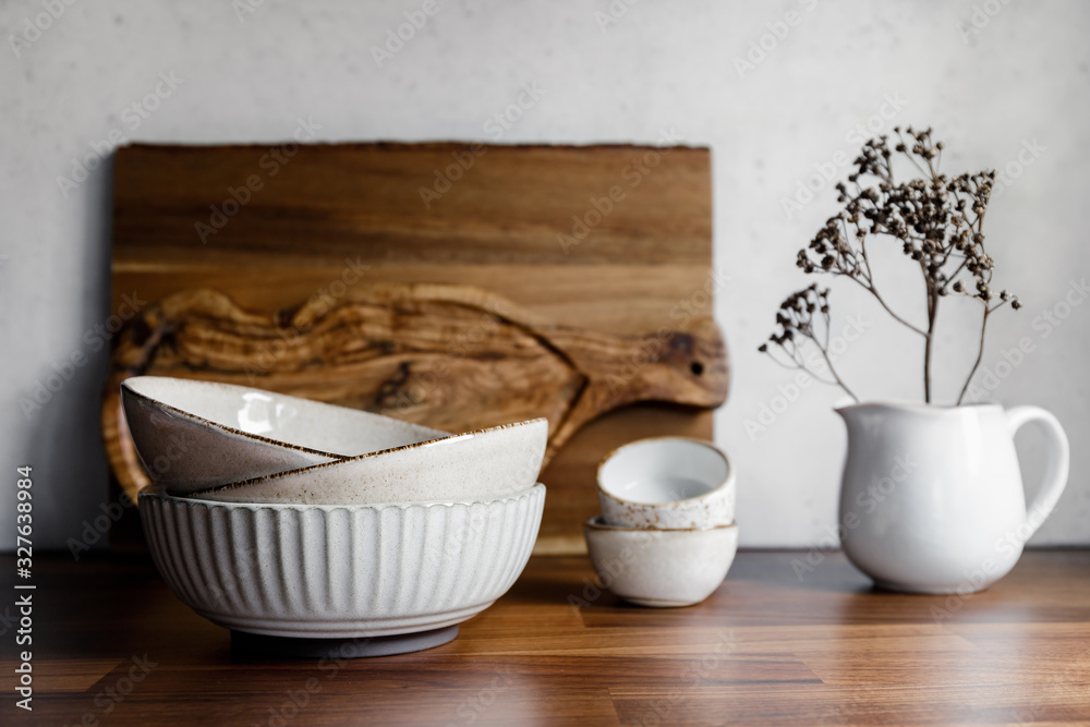 Set of kitchen ceramic tableware and wooden cutting boards on a table. Eco style home still life.