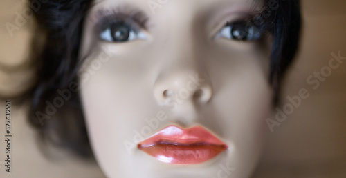 Artificial beauty concept  portrait of perfect plastic mannequin with red glowing lipstick on fake lips. Focus on mouth  shallow depth of field.