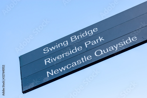 Black directional sign indicating the way to the following destinations: Swing Bridge, Riverside Park and Newcastle Quayside
