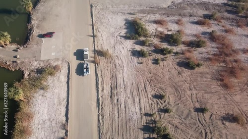 Aerial view of truck towing boat on gravel road along lake - Yuma Arizona