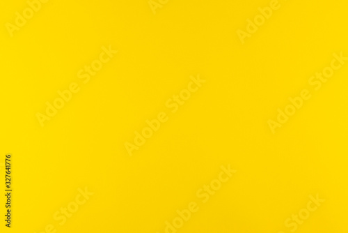 Yellow background of real colored paper, illuminated by a soft light on the sides.