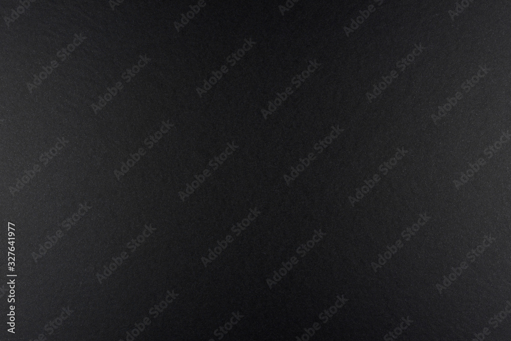 Black background made of real black paper with a matt fibrous structure, illuminated by a soft light on the sides.