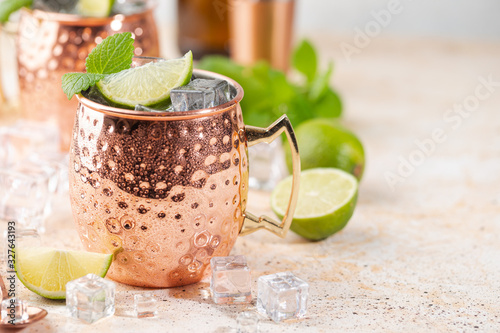 Cold Moscow Mules cocktail with ginger beer, vodka, lime. White stone background.