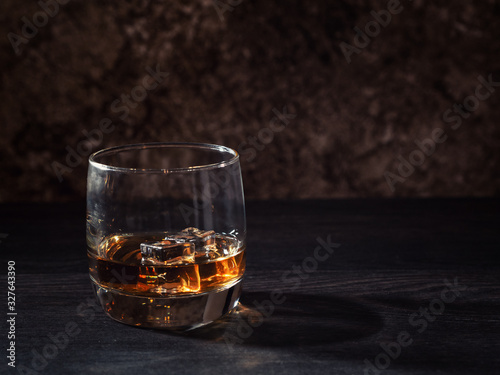 Whiskey splash in a glass with ice on a wooden table