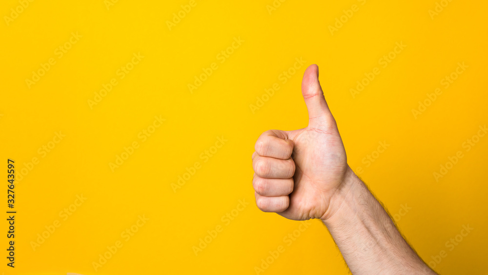 closeup hand with big thumb down over a wide yellow banner background with copyspace. dislike sign