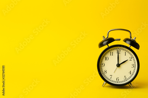 Time background concept. Vintage classic alarm clock on yellow empty background. Time management concept