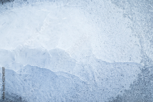 Close-up of cracked ice on a frozen lake in the winter, viewed from above. Abstract full frame background. Copy space, top view.