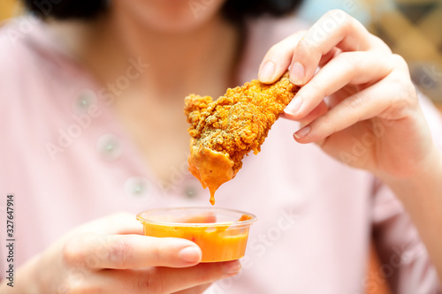 Holding the fried chicken, dip it into the sauce. fast food restaurant.