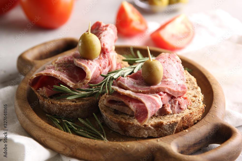 Lunch. Ham sandwiches on a wooden board. Olives, tomatoes and rosemary on a light background. Background image, copy space