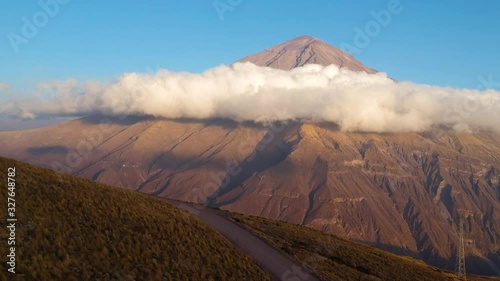 Peruvian Misti Volcano with clouds below its peak. Aerial rising.