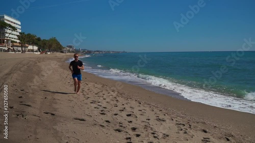 Caucasian man running along the beach seen ahead photo