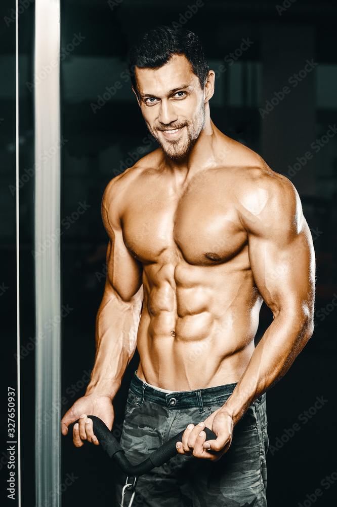 Fototapeta premium Bodybuilder strong man pumping up biceps muscles