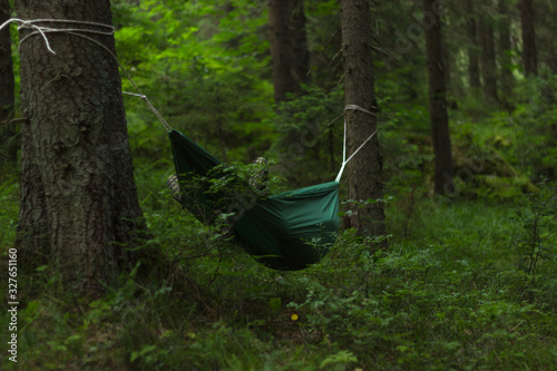 Hammock in the middle of the woods. Green forest background. Relax in nature