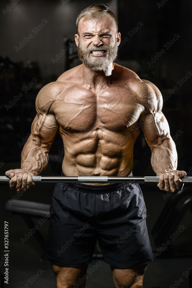 Bodybuilder strong man pumping up biceps muscles
