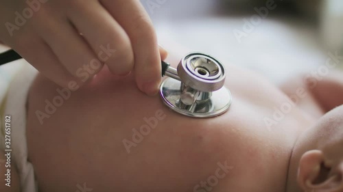 Close slow motion shot of a newborn being ascultated in the abdomen.