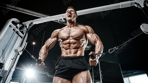 Muscular bodybuilder at cable crossovers fitness