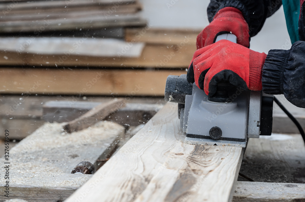 Worker whittling wood outdoor using electric planer Worker whittling wood outdoor using electric planer