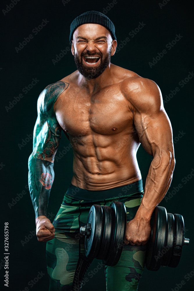 Man athlete bodybuilder. Muscular young fitness sports guy doing workout with dumbbell in fitness gym