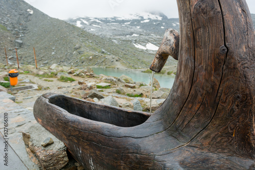 Water pipe with basin made out of old wooden trunk.