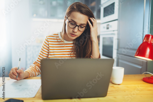 Online education, Beautiful student girl in eyeglasses studying at home using modern laptop, pretty woman making courses on literature or premium business courses for executives from home on notebook