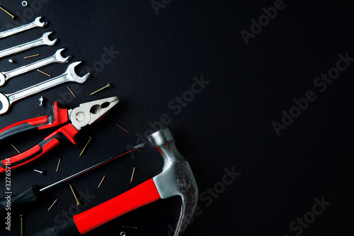 Construction tools for home renovation on black background. Red hammer, pliers, screwdriver, wrenches, screws. Maintenance, reparing concept. Place for text, flat lay. photo