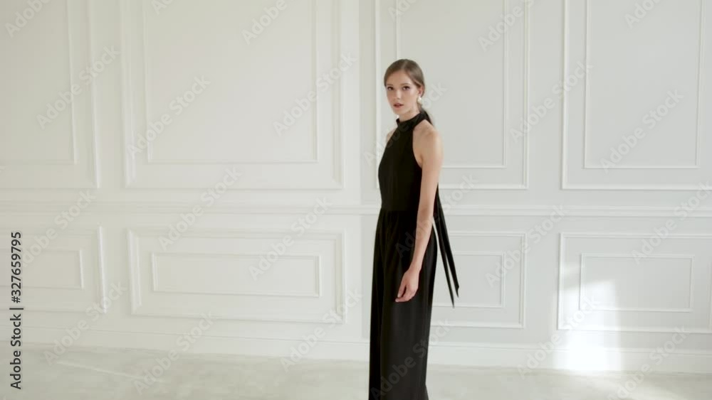 beautiful girl in black clothes walks in a white room