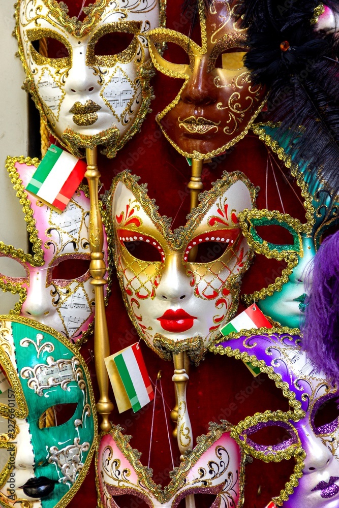 A portrait of a venetian carnival mask surrounded by other of the same mysterious masks in a shop. Ready to be bought and to hide your identity at a masked or costumed ball or maybe halloween.