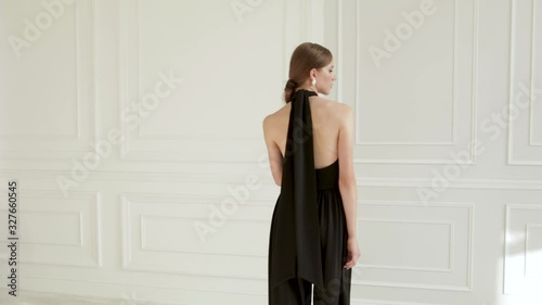 beautiful girl in black clothes walks in a white room