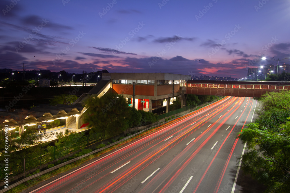 Fototapeta premium Sunset, the night in metropolis, train station and vehicles in transit. Sao Paulo city highway beside the river. Skyline, cars and traffic on the road at high speed.
