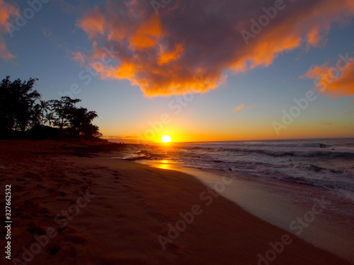Beautiful Sunset over the ocean and beach with waves moving to shore and foot prints in the sand